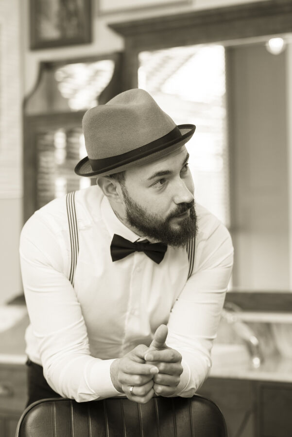 Daniele Vitale mit Hut und Fliege am Barberstuhl